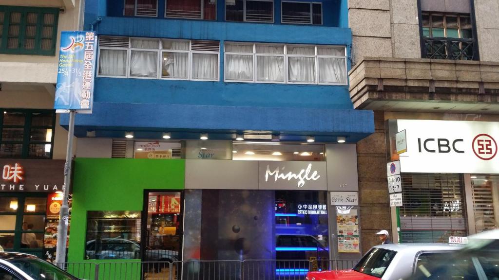 um edifício azul e verde com carros estacionados em frente em Mingle by The Park em Hong Kong