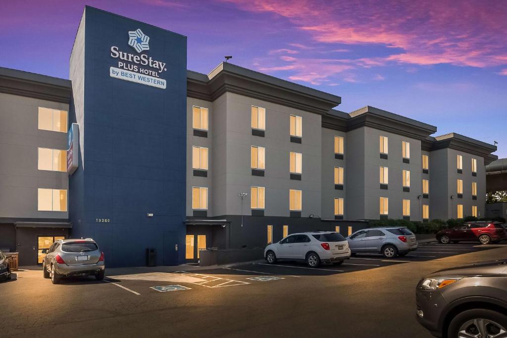 a building with cars parked in a parking lot at SureStay Plus Hotel by Best Western SeaTac Airport in SeaTac