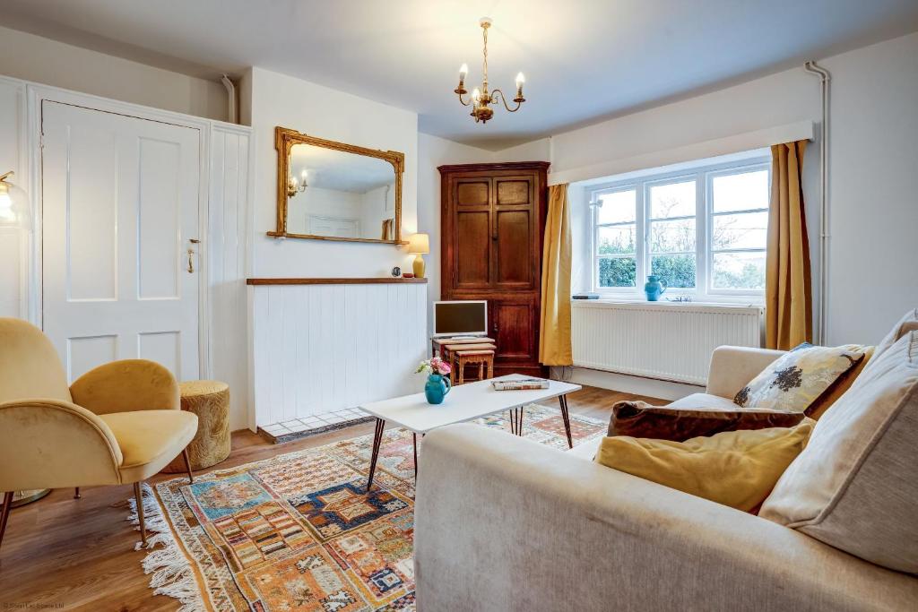 a living room with a couch and a mirror at Windrush Cottage in Long Hanborough