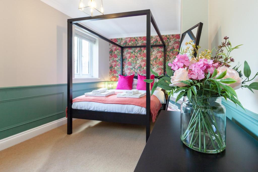 1 dormitorio con 1 cama con un jarrón de flores sobre una mesa en A gem nestled in the heart of Oxford with parking!, en Oxford