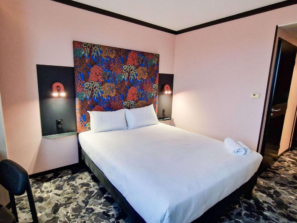 ディジョンにあるIbis Styles Dijon Nord Valmyのベッドルーム1室(壁に絵画が描かれた白い大型ベッド1台付)