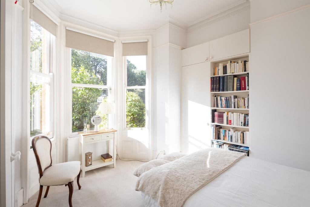 a white bedroom with a bed and a book shelf at Veeve - Courtside Charms in London