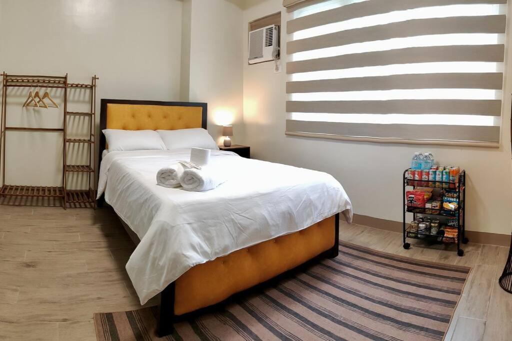 - une chambre avec un grand lit et des draps blancs dans l'établissement Cozy studio w/ Nintendo Switch, à Bacolod