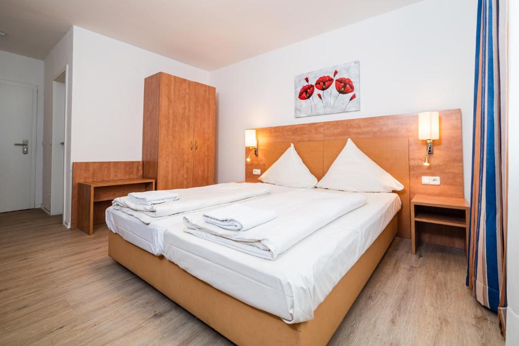 1 dormitorio con 1 cama grande con sábanas blancas en G & L Hotel Dortmund, en Dortmund