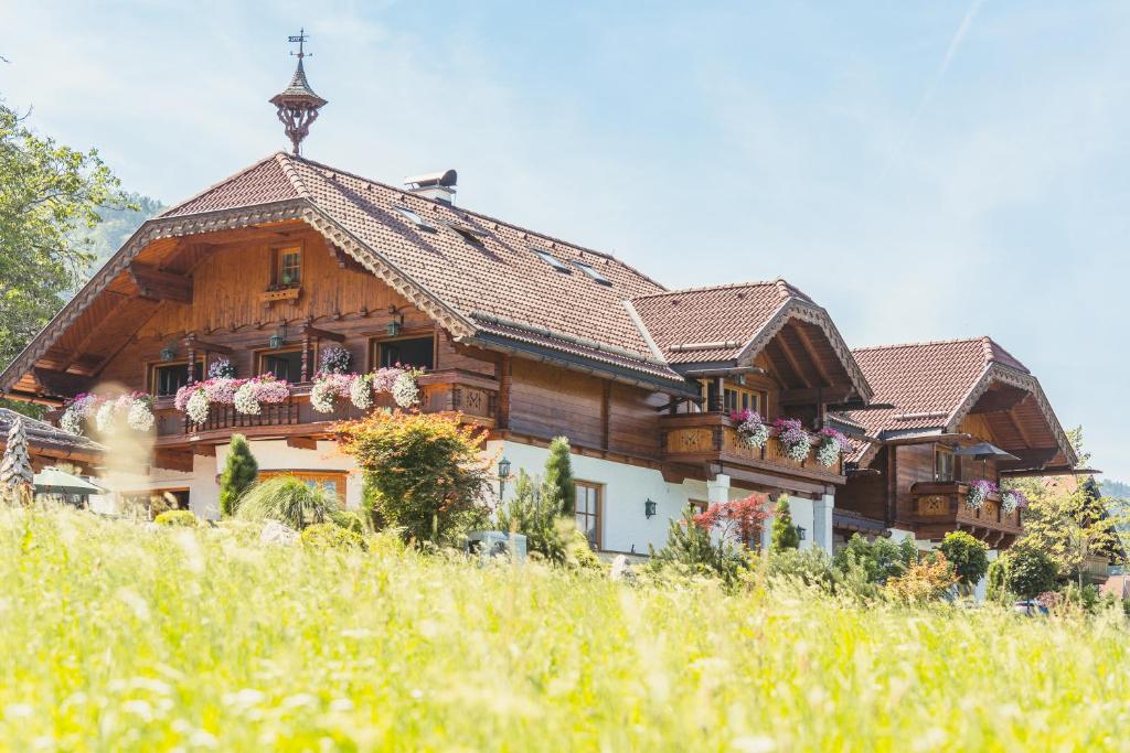una gran casa de madera con flores en el balcón en Ferienwohnung Schossleitner - der Wohlfühl-Ansitz am Wolfgangsee mit Weitblick, en Sankt Gilgen