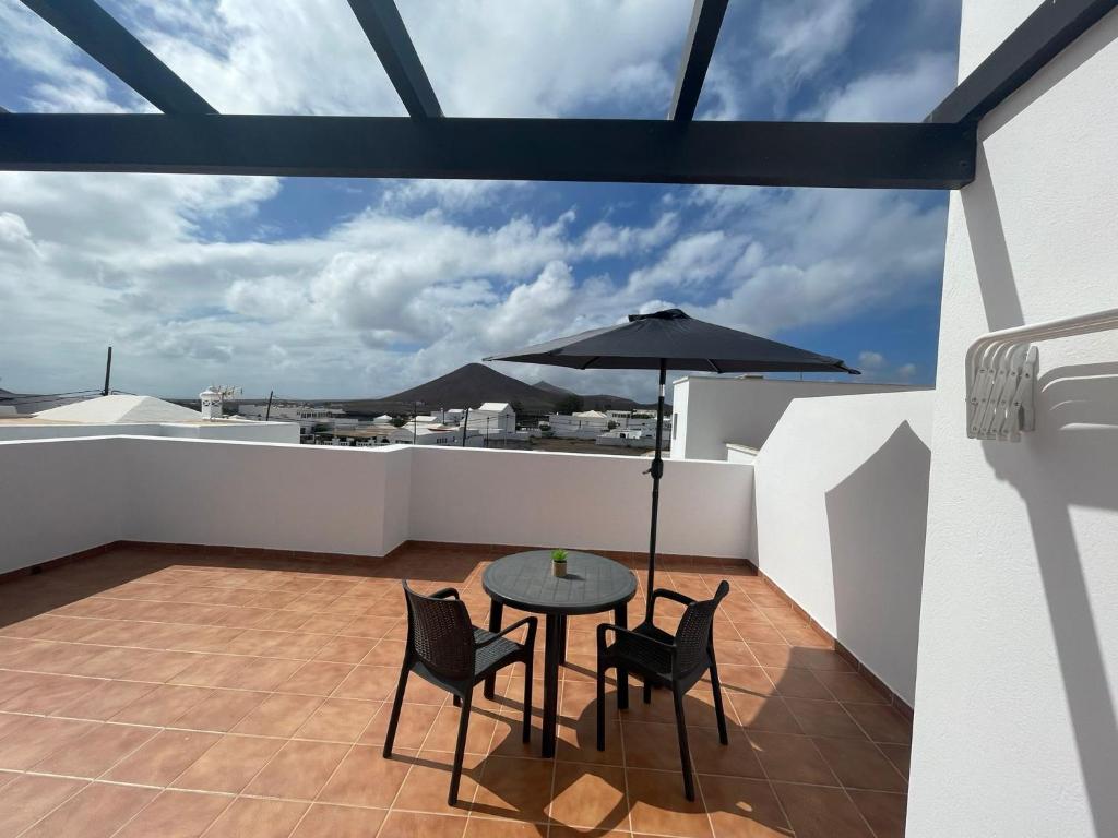 balcón con mesa, sillas y sombrilla en Casa volcán, en Tahiche