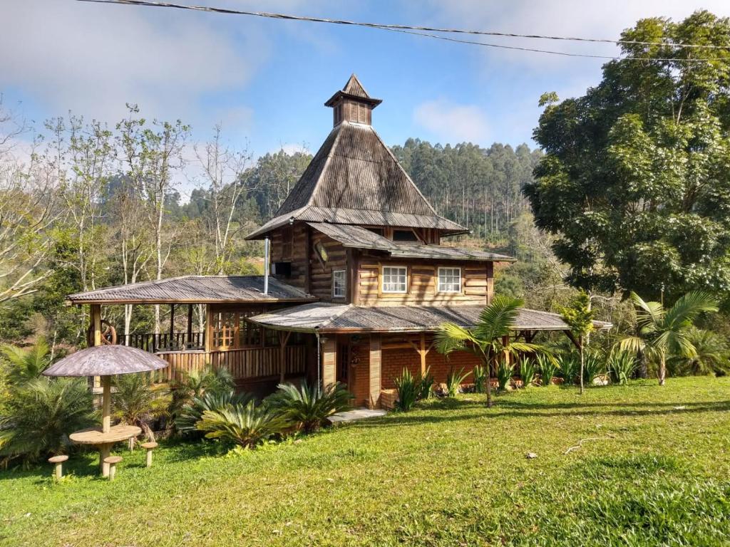 a house with a thatched roof in a field at Casa Meu Céu in Itá