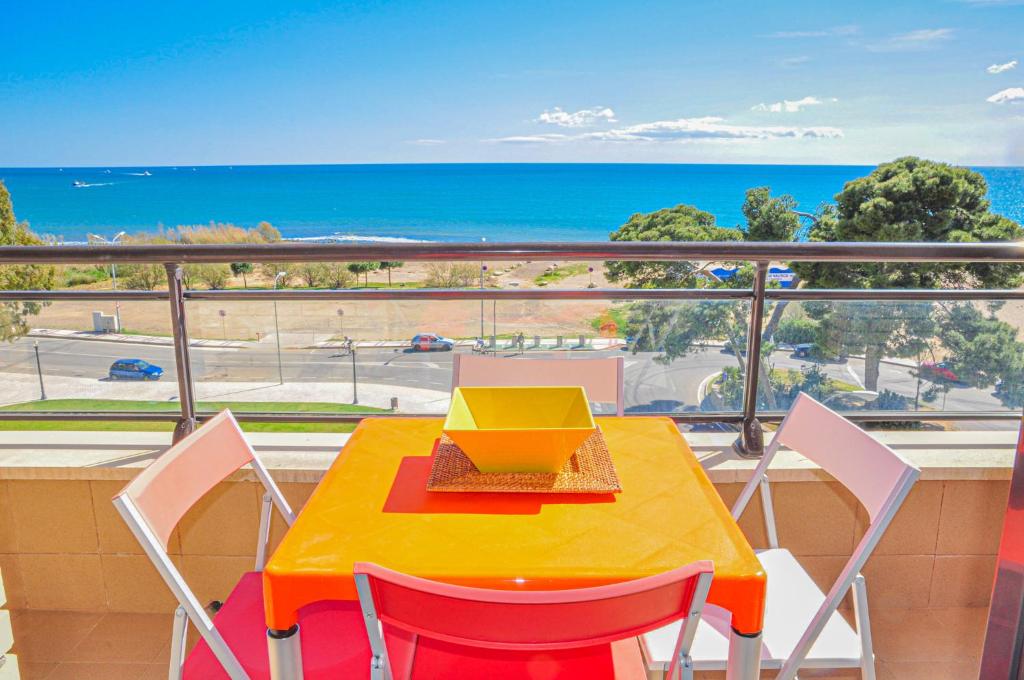 una mesa amarilla y sillas en un balcón con vistas al océano en La Salle Litoral - ONLY FAMILIES, en Cambrils