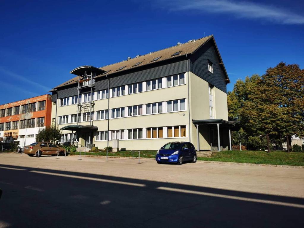 un coche azul estacionado frente a un edificio en Híd Ifjúsági Szálló en Dunaújváros
