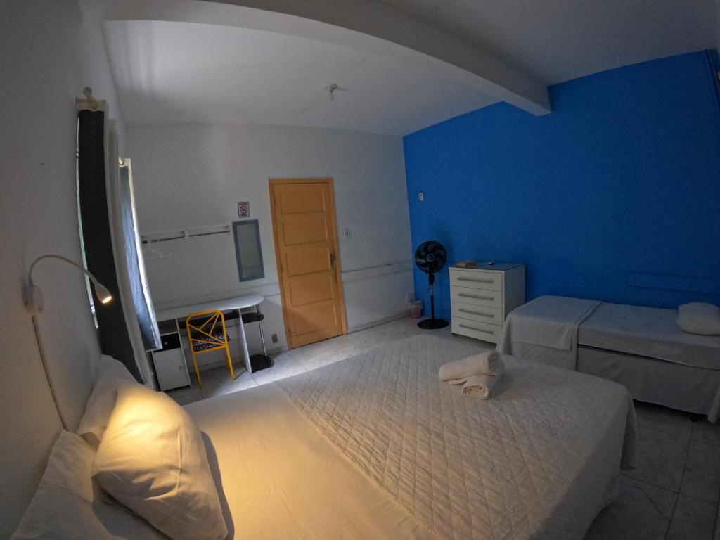 a blue bedroom with two beds and a desk at Nomads Hostel Multicultural & Coworking in Salvador