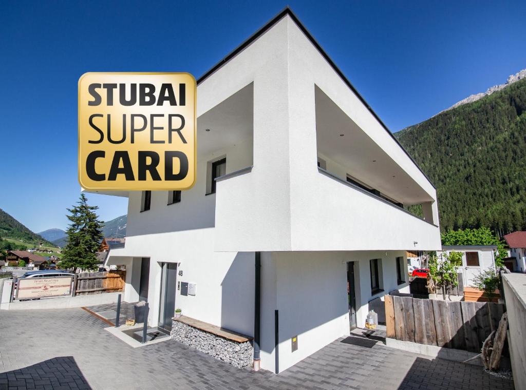 een wit gebouw met een bord met stomme superkaart bij Haus Finca in Neustift im Stubaital