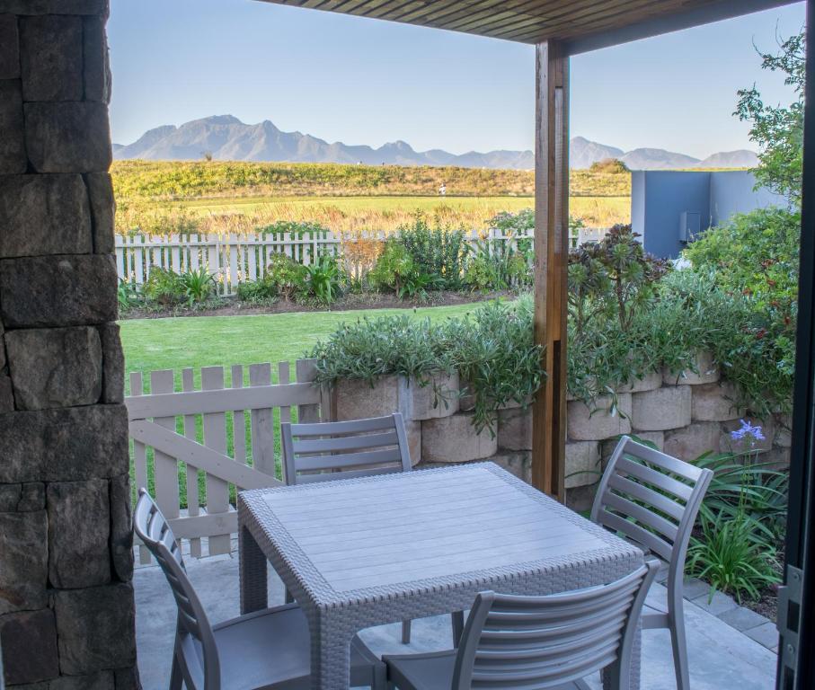 a table and chairs on a patio with mountains in the background at Vista Views in Herolds Bay