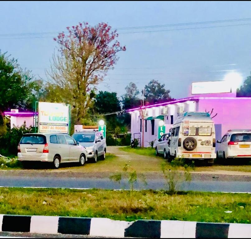a group of cars parked in front of a pink building at TOURIST LODGE in Surajpur Jikkla
