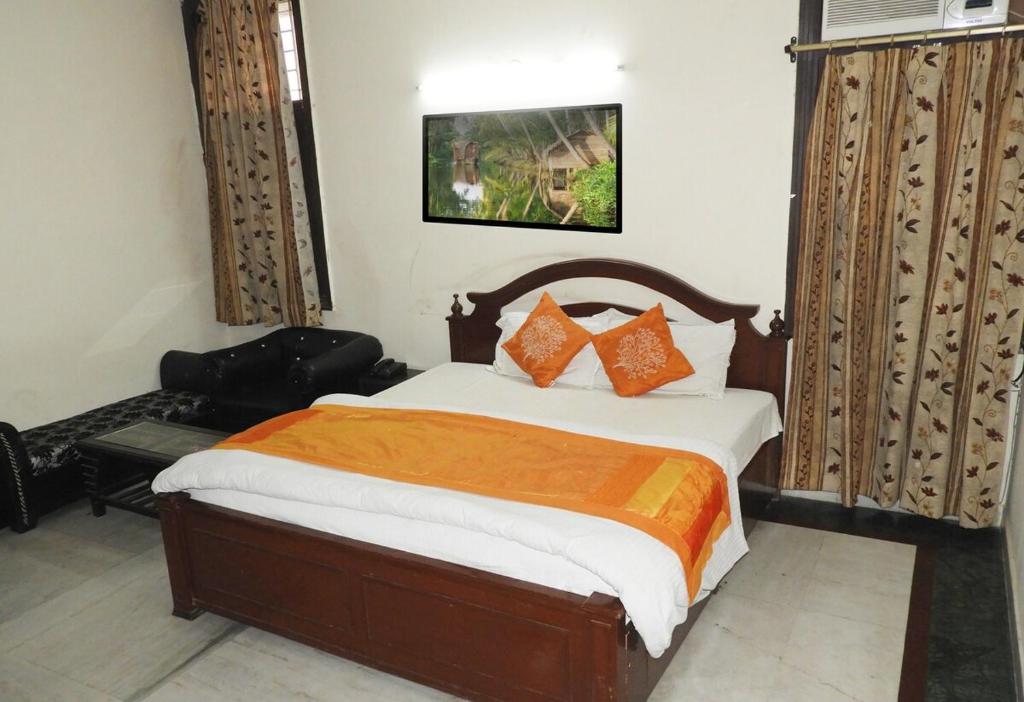 um quarto com uma cama grande e almofadas laranja em HOTEL JKM PALACE Near Apollo Hospital em Nova Deli