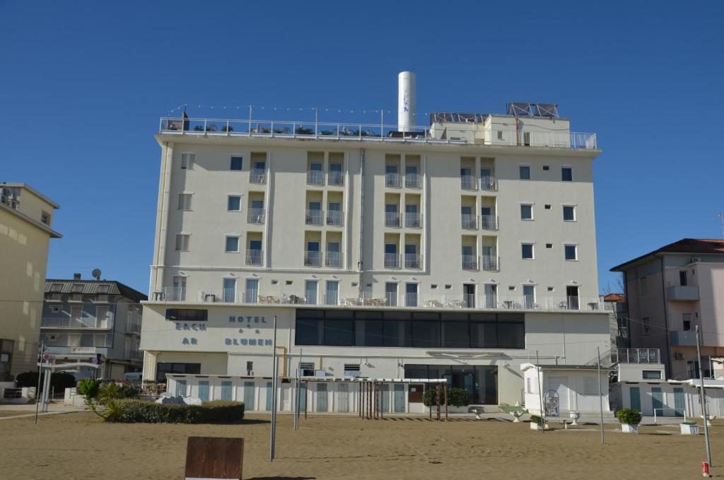 duży biały budynek na plaży z budynkami w obiekcie Hotel Blumen w Rimini