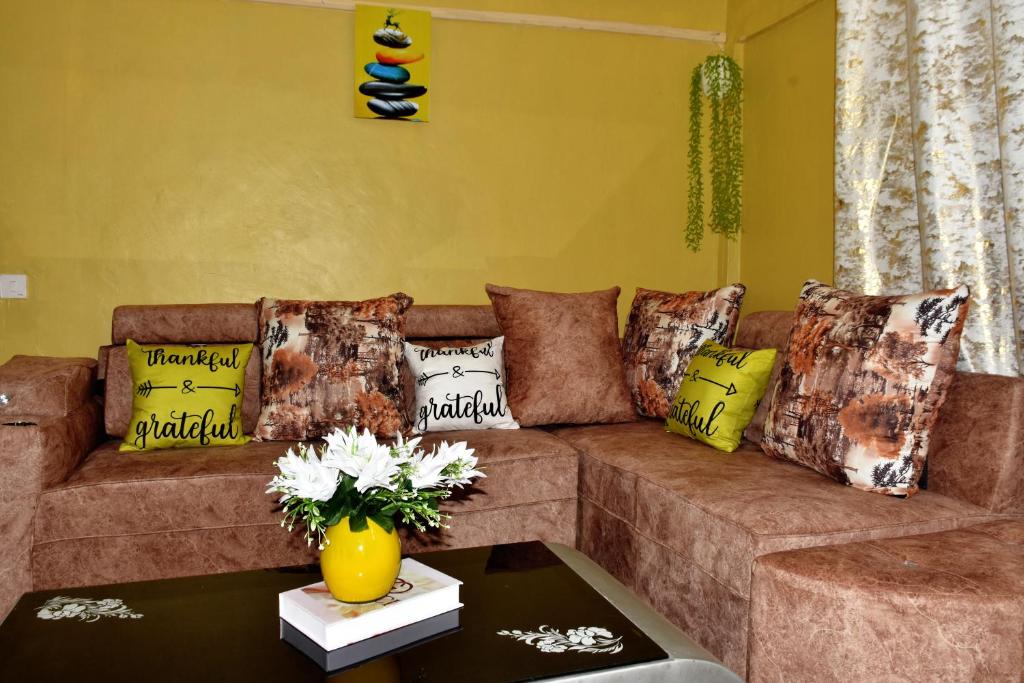 a living room with a brown couch with colorful pillows at one bedroom in oj town ruiru in Kiambu