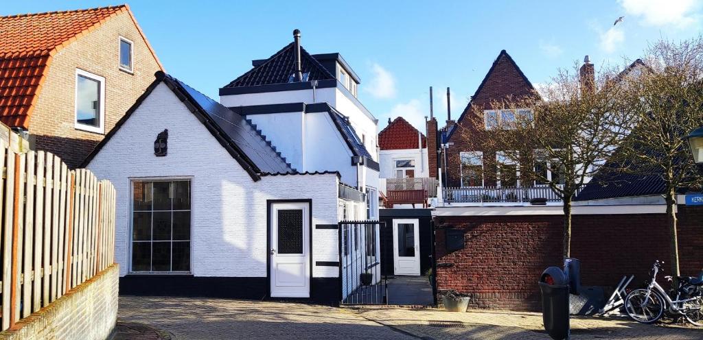 uma casa branca com um portão e um edifício de tijolos em B&B de Drukkerij Zandvoort - luxury private guesthouse em Zandvoort