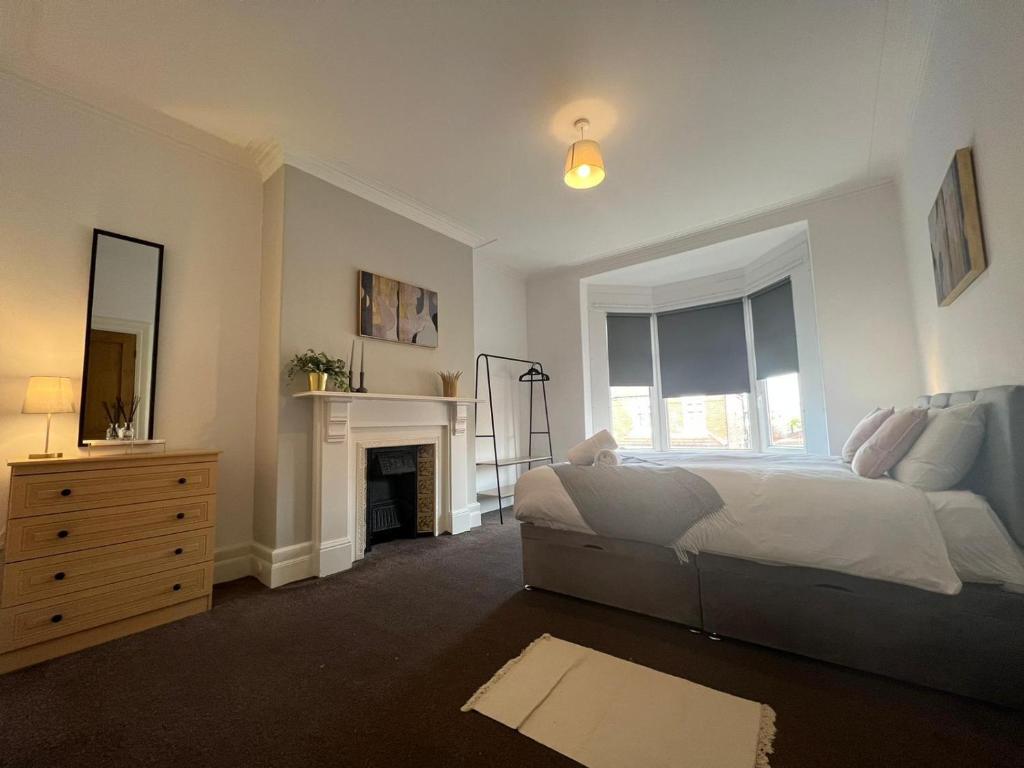 a white bedroom with a bed and a fireplace at Alexander Apartments West Harton in South Shields