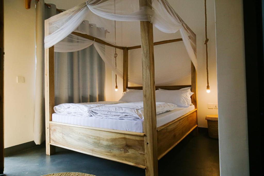 a bedroom with a wooden bunk bed with white sheets at Hakuna Woga Inn in Arusha