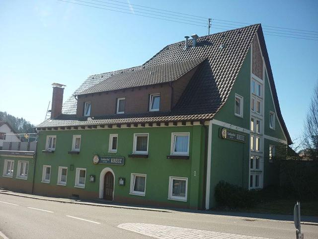 un bâtiment vert avec un toit sur le côté d'une rue dans l'établissement Landgasthof Kreuz mit Gästehaus, à Immendingen