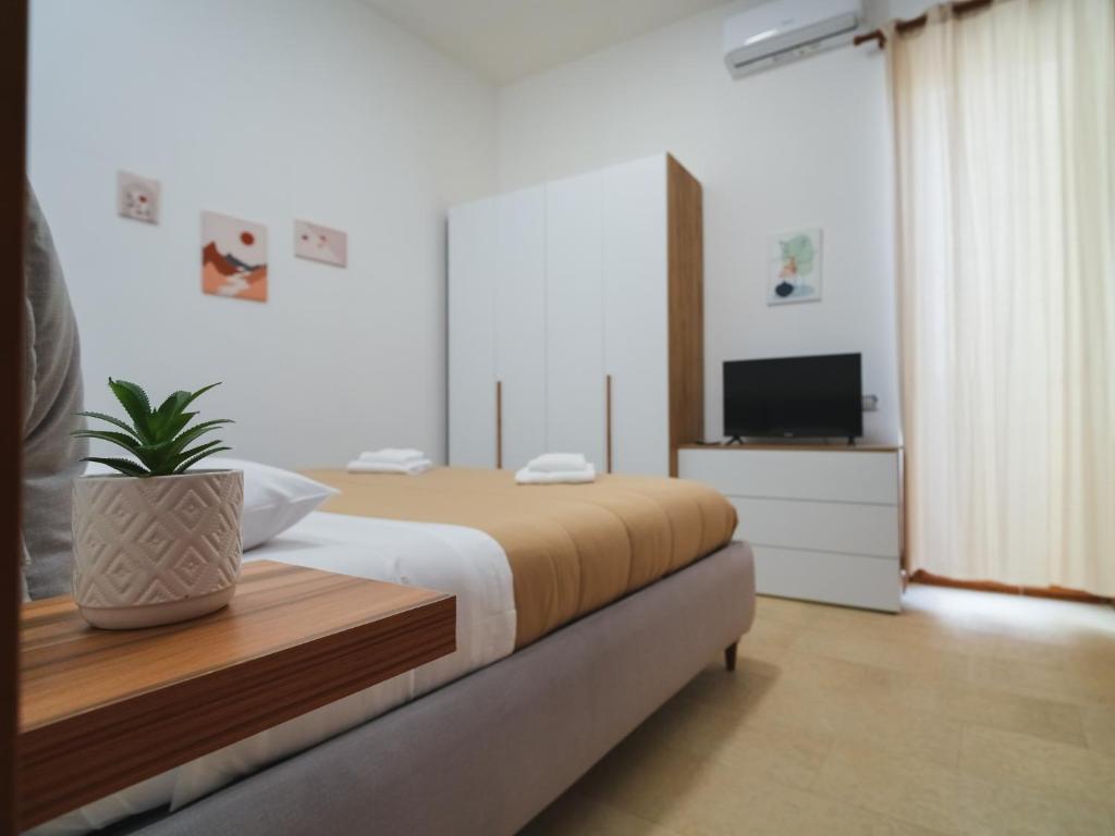 um quarto com uma cama e uma televisão e um vaso de plantas em Da Sara em Pozzuoli