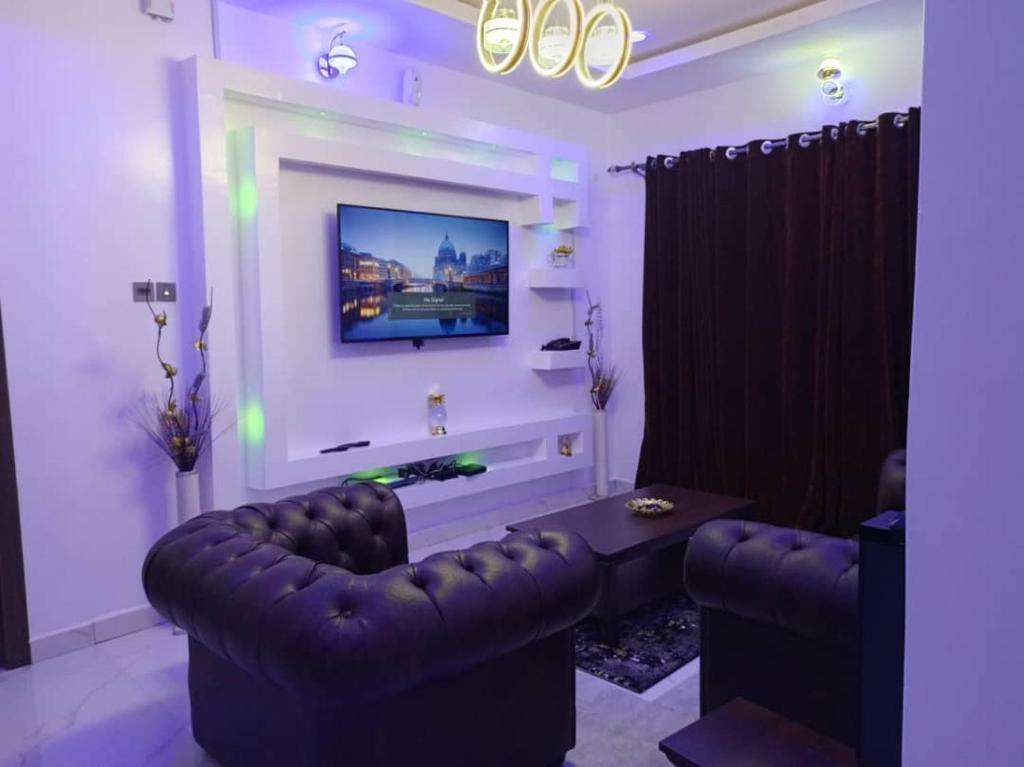 - un salon avec un canapé et une télévision murale dans l'établissement HKB APARTMENTS, à Ibadan