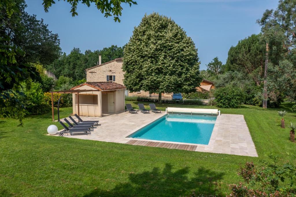 a pool in a yard with chairs and a house at Domaine De Cimélia in Fauch