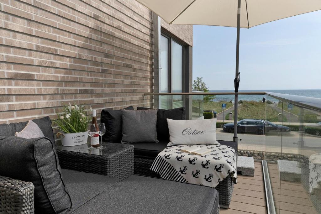 eine Terrasse mit einem Sofa, einem Tisch und einem Sonnenschirm in der Unterkunft Meerlust in Scharbeutz