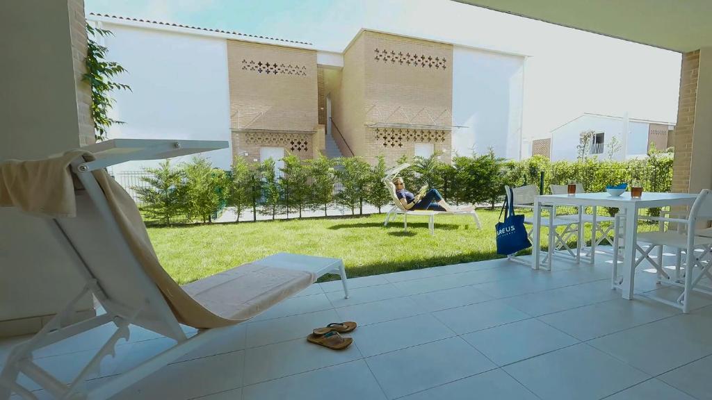 a woman sitting on a balcony with a table and chairs at Pareus Beach Resort in Caorle