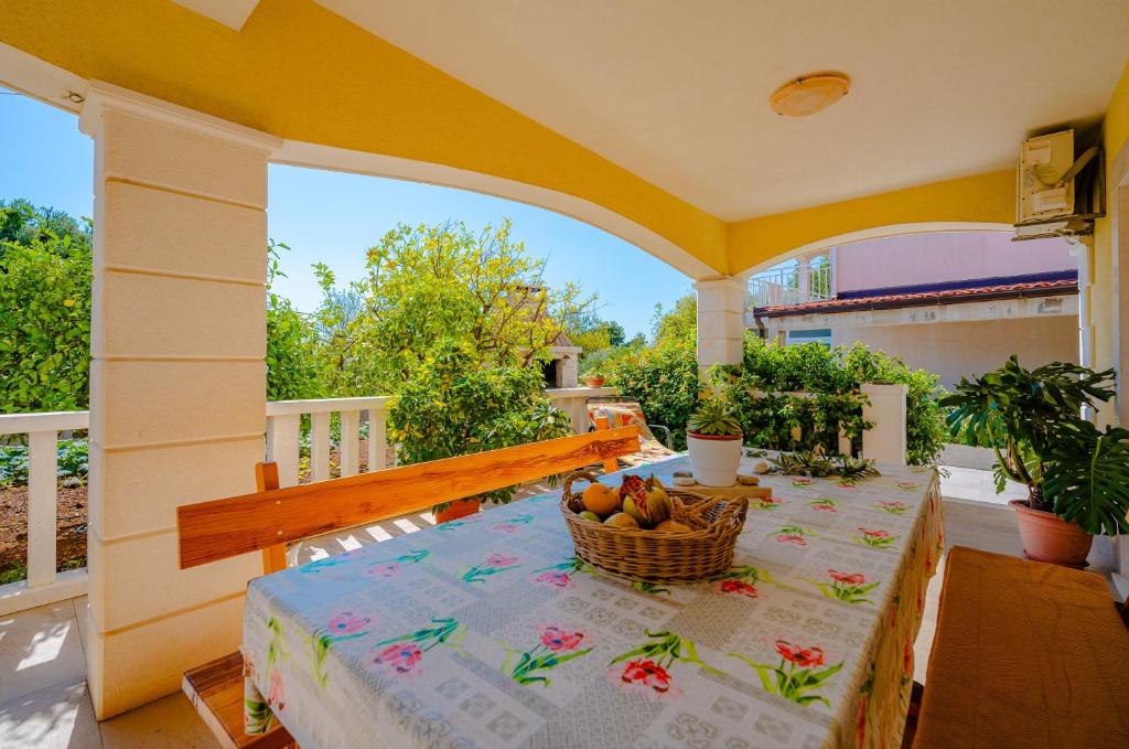 a table with a basket of fruit on a porch at Apartments Mladenka in Orebić