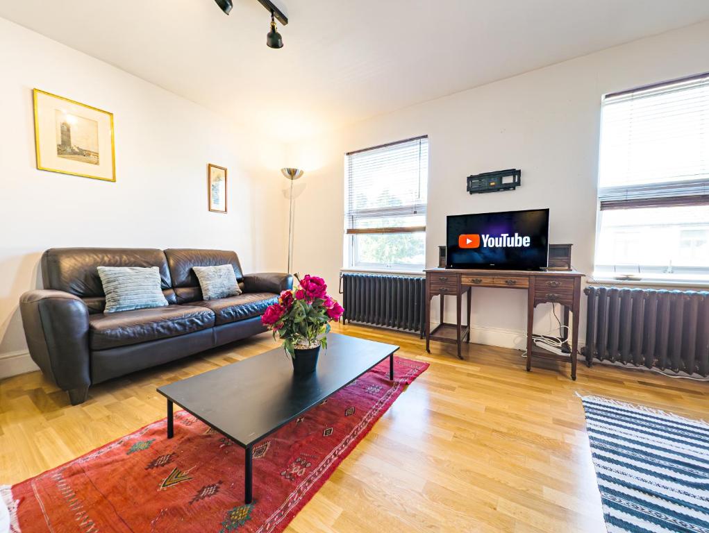 a living room with a couch and a tv at Spacious 2 Bedroom Apartment in Hackney in London