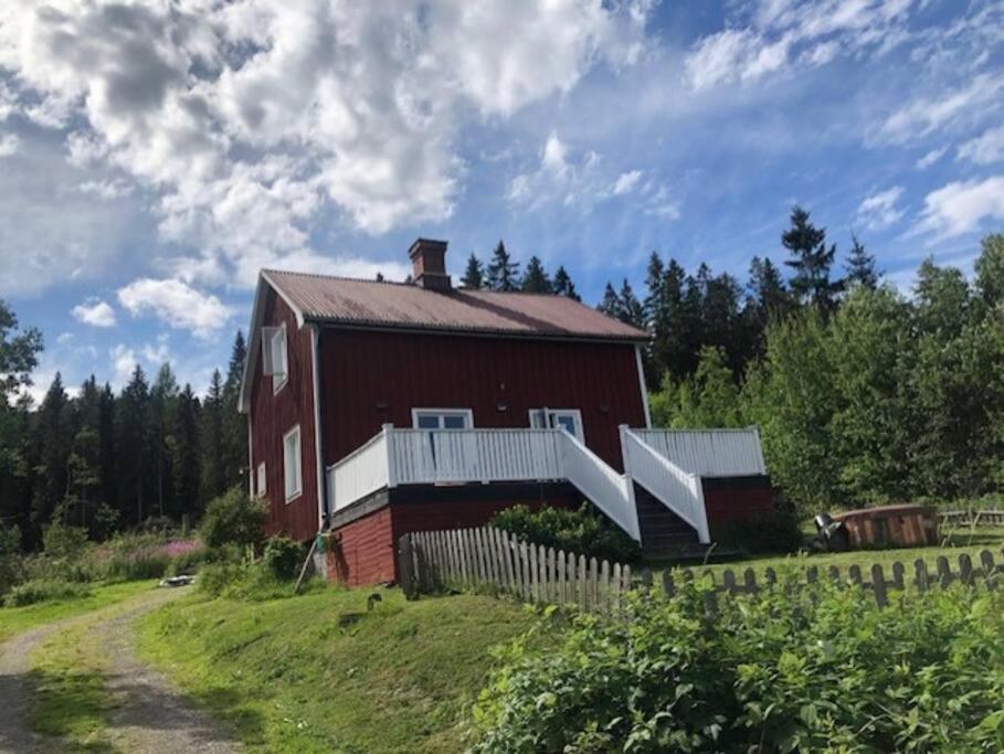 un granero rojo con una valla al lado de un camino de tierra en Huset i skogen med utsikten en Vallsta