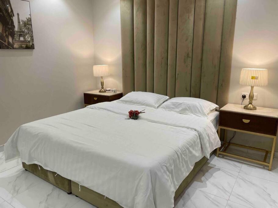 um quarto com uma cama com lençóis brancos e flores em شقة عصرية واسعة بغرفتي نوم موقع مميز وسط المدينة em Riyadh