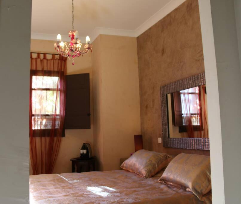 um quarto com uma cama, um espelho e um lustre em Suite Bradia, Riad 2 Couple only au village naturiste em Cap d'Agde