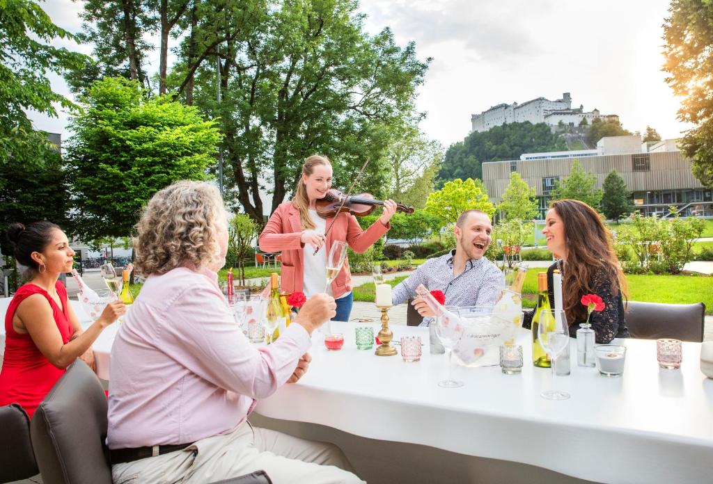 eine Gruppe von Menschen, die an einem Tisch sitzen und Wein trinken in der Unterkunft JUFA Hotel Salzburg in Salzburg
