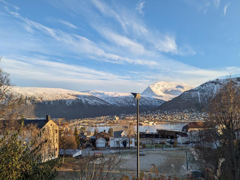 una ciudad con montañas cubiertas de nieve en el fondo en Mountain & Sea View Apartment Tromsø, en Tromsø
