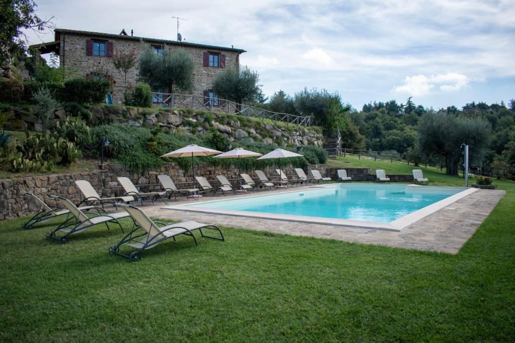 una piscina con sedie a sdraio e una casa di Villa Val di Luce - Homelike Villas a Umbertide