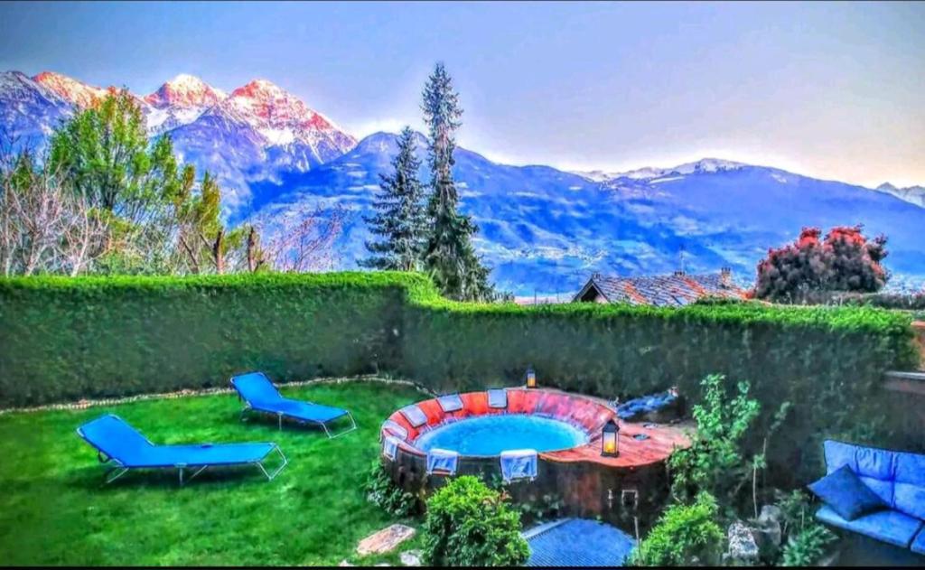 d'un jardin avec une table, des chaises et des montagnes. dans l'établissement Villa Panoramica - 200Mq - SPA - Giardino Privato - 0039-34893-66818, à Aoste