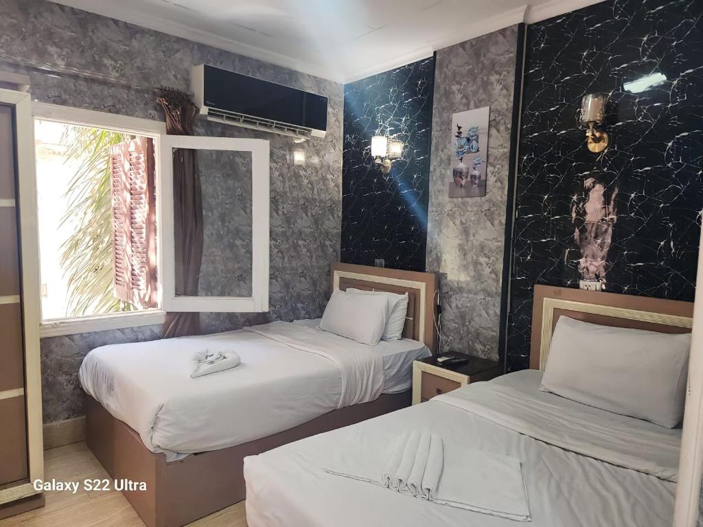 a hotel room with two beds and a window at Magic Hotel in Cairo