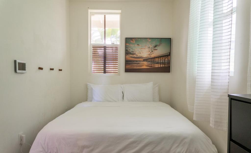 a white bed in a white bedroom with a window at Hummingbird Oceanfront Cottage in Hauula