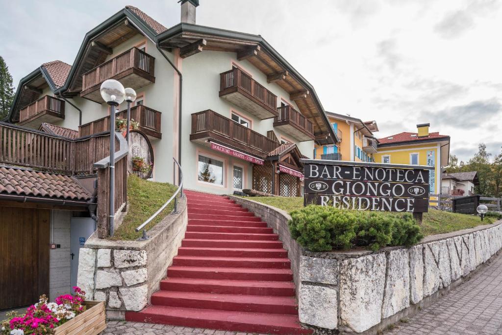 un edificio con una escalera roja delante de él en Giongo Residence Aparthotel 201 en Lavarone