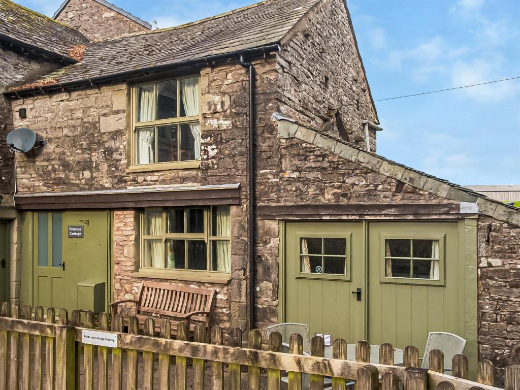 シャップにあるPrimrose Cottageの緑の扉と木の柵のある石造りの家