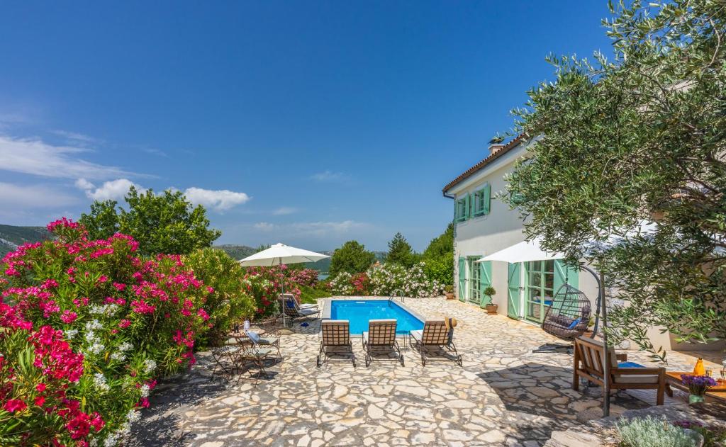 a villa with a swimming pool and chairs and flowers at Villa Tribalj in Tribalj