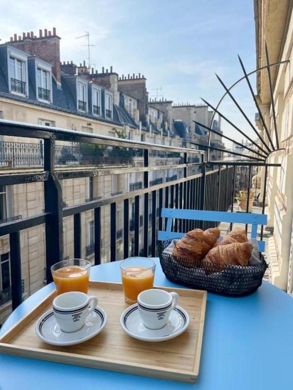 - une table avec deux tasses de café et de pain sur le balcon dans l'établissement PERGO, à Paris