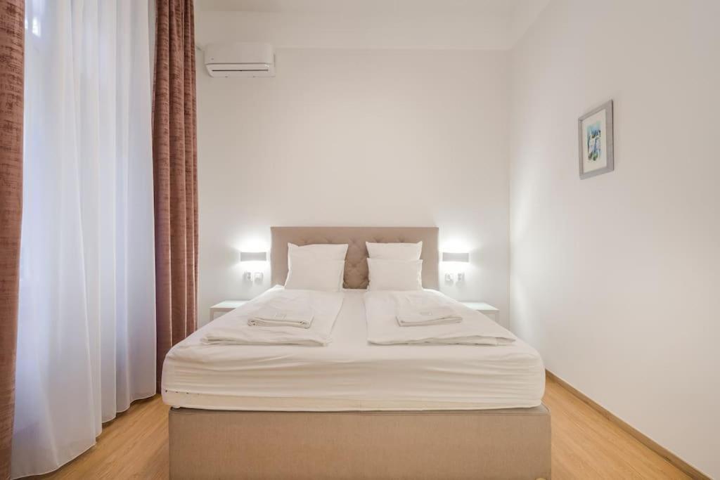 a bedroom with a large bed with white sheets at Klauzál Garden City Apartments- studio K32 in Budapest