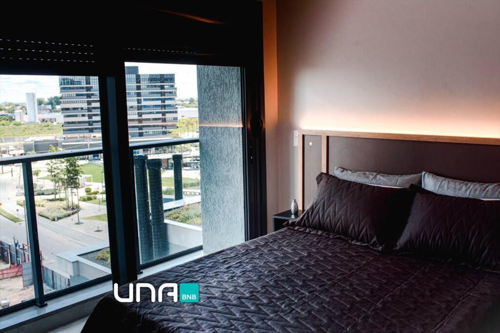 una camera da letto con un letto e una grande finestra di Loft divino no Parque Una a Pelotas