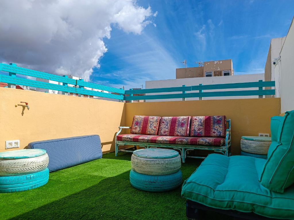 d'une terrasse avec un canapé et des chaises sur un balcon. dans l'établissement Daydream Medano Coliving, à El Médano