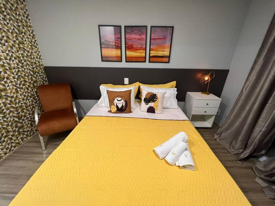 a bedroom with a yellow bed with a yellow blanket at Novo Studio Coral Metrô Belém com Piscina in Sao Paulo