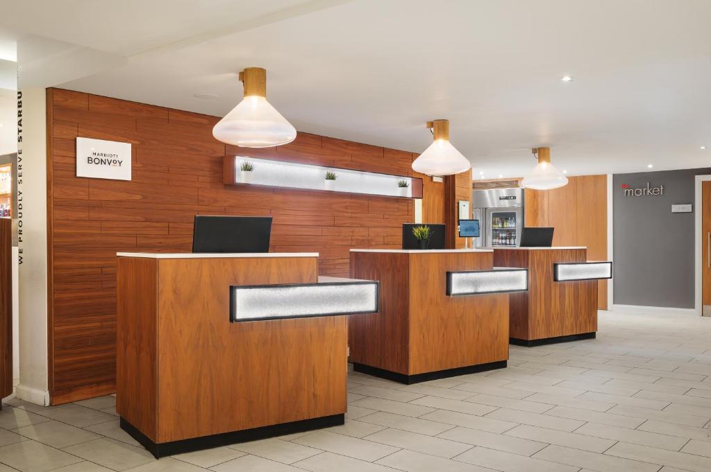 a lobby of a hotel with wooden desks and pendant lights at Courtyard by Marriott Glasgow Airport in Paisley