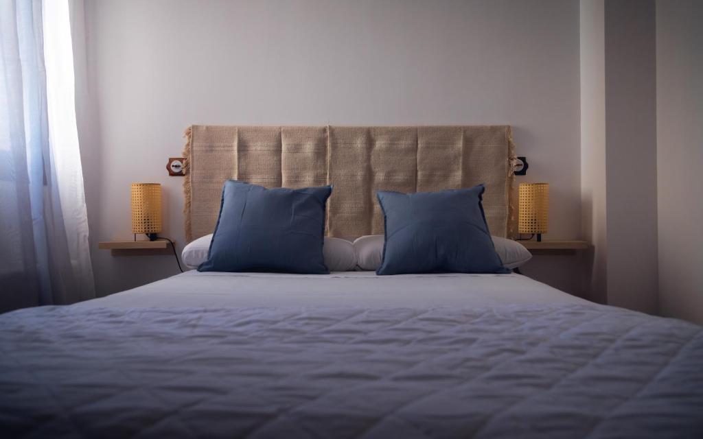 a bedroom with a bed with blue pillows and two lamps at Hostal Corper Navalcarnero in Navalcarnero